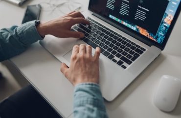 person wearing long-sleeve top working on laptop