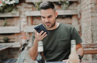 man in gray crew neck long sleeve shirt holding black smartphone