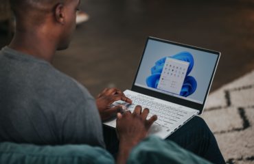 man in gray long sleeve shirt using Windows 11 computer